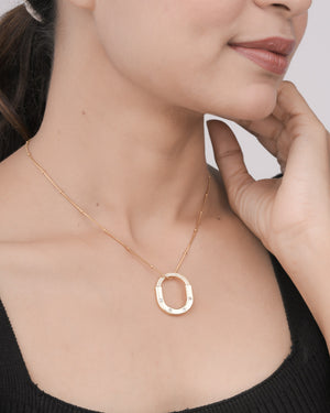 Close-up of woman wearing gold fashion necklace with oval pendant and small crystals on thin chain