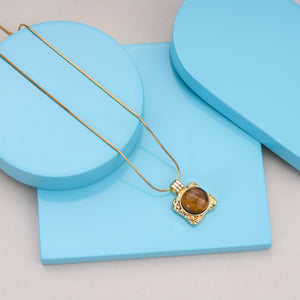 Gold necklace with tiger eye gemstone pendant on light blue display blocks