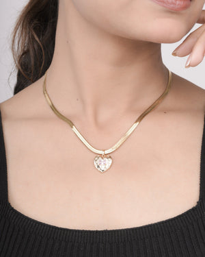 Close-up of woman wearing gold heart pendant necklace with pink gemstone on gold chain