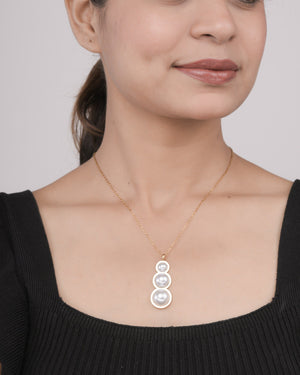Close-up of woman wearing gold chain necklace with three pearl pendant in descending size