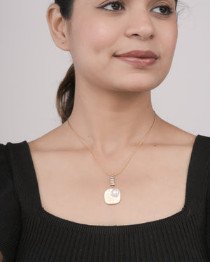 Close-up of woman wearing gold necklace with butterfly design and pearl pendant on black top