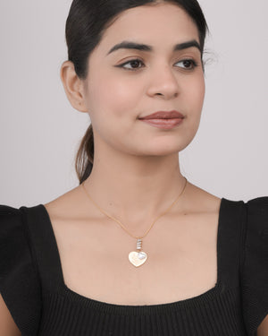 Woman wearing a gold heart-shaped pendant necklace with pearl detail, styled with a black top