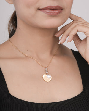Close-up of woman wearing a gold heart pendant necklace with pearl detail and crystal accents on gold chain