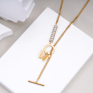 Gold chain necklace with butterfly charm and rectangular crystal accents on white display