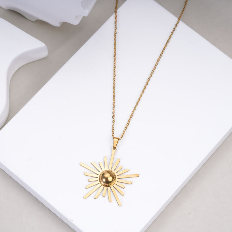 Gold sunburst pendant necklace on white jewelry display, fashion jewelry by Maniyar Bazaar
